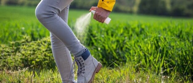 Woman spraying ankles in field