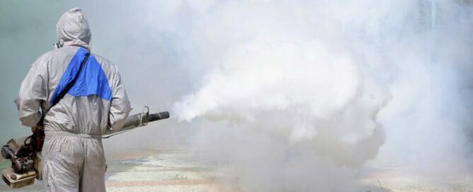 Pest control worker using large fogging machine to spray for pests