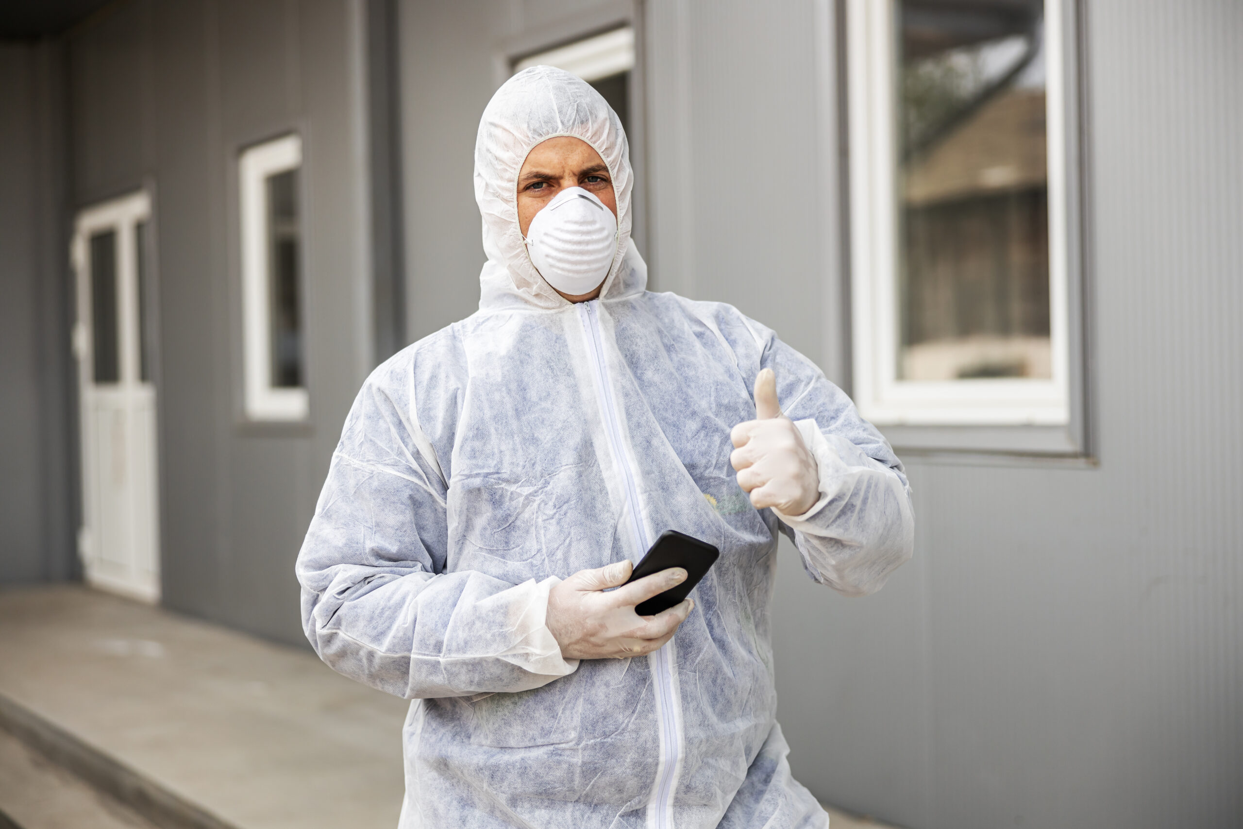 Person in protective suit, standing outisde of house.